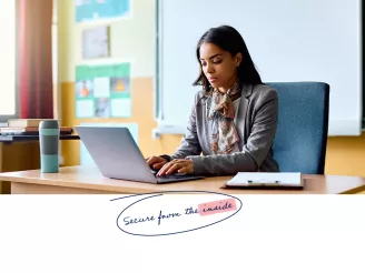 Teacher working on laptop in classroom