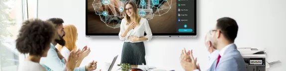 Office workers clapping in meeting room with a presentation on screen and a printer at the side